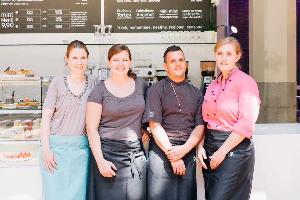 Four persons stand in front of a menu