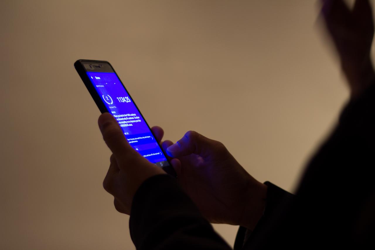 Hands operate a mobile phone with a blue screen