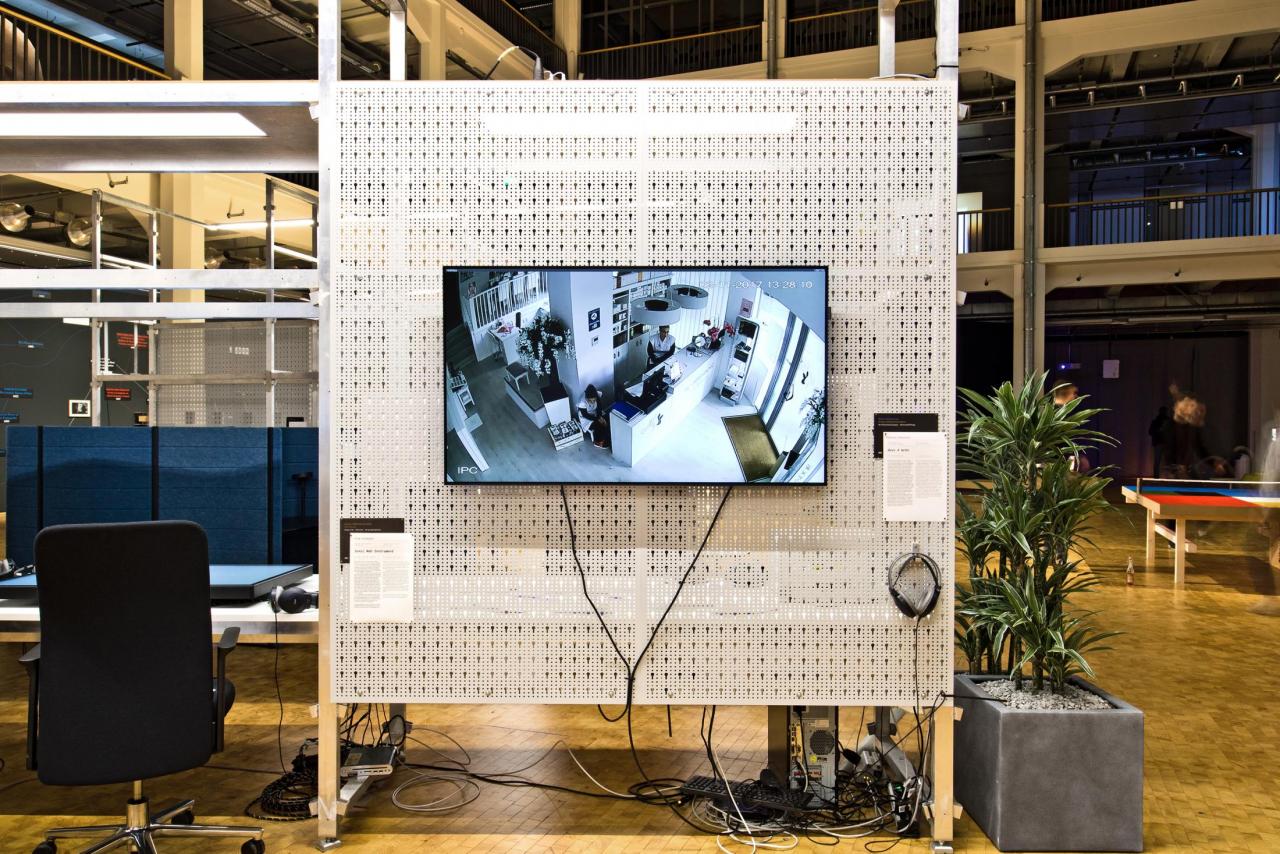 The exhibition view shows a screen with a room shot on a partition wall