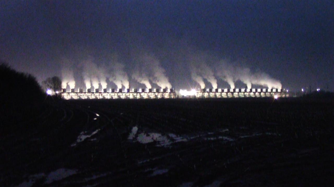 Night photography in dark blue tones with light and smoke on the horizon