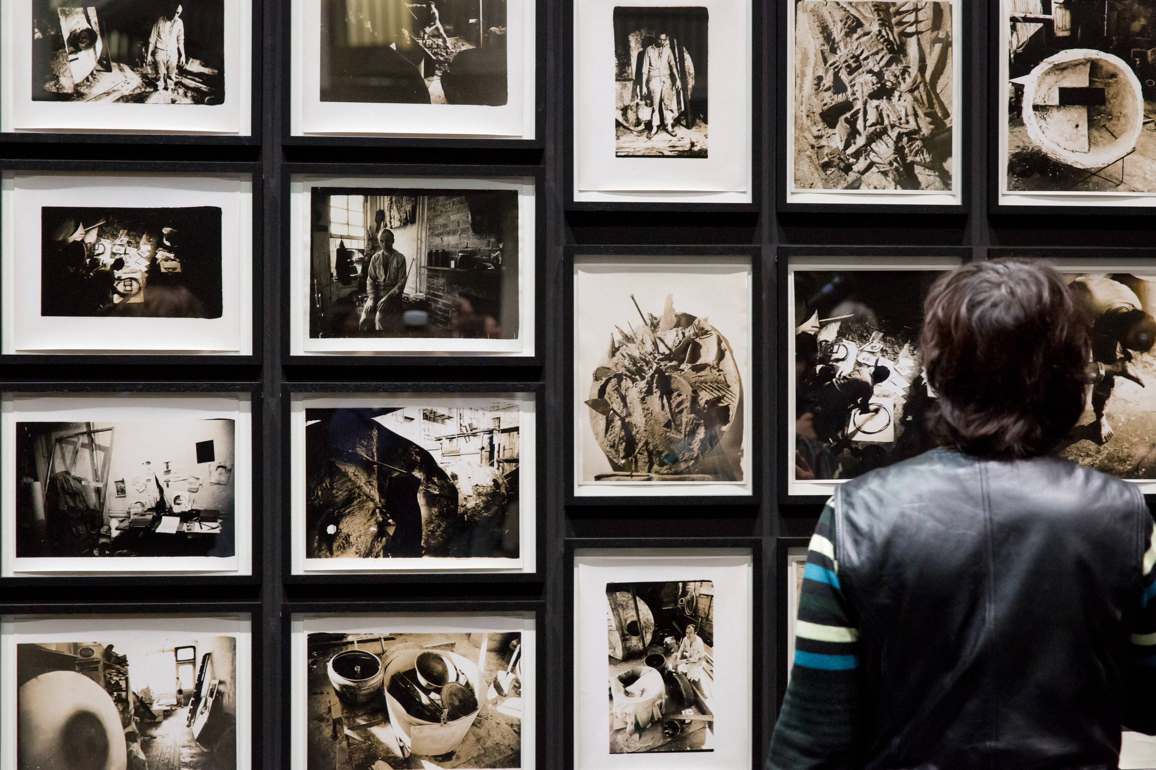 The photo shows the back view of a man in front of several black and white photographs of Tambellini