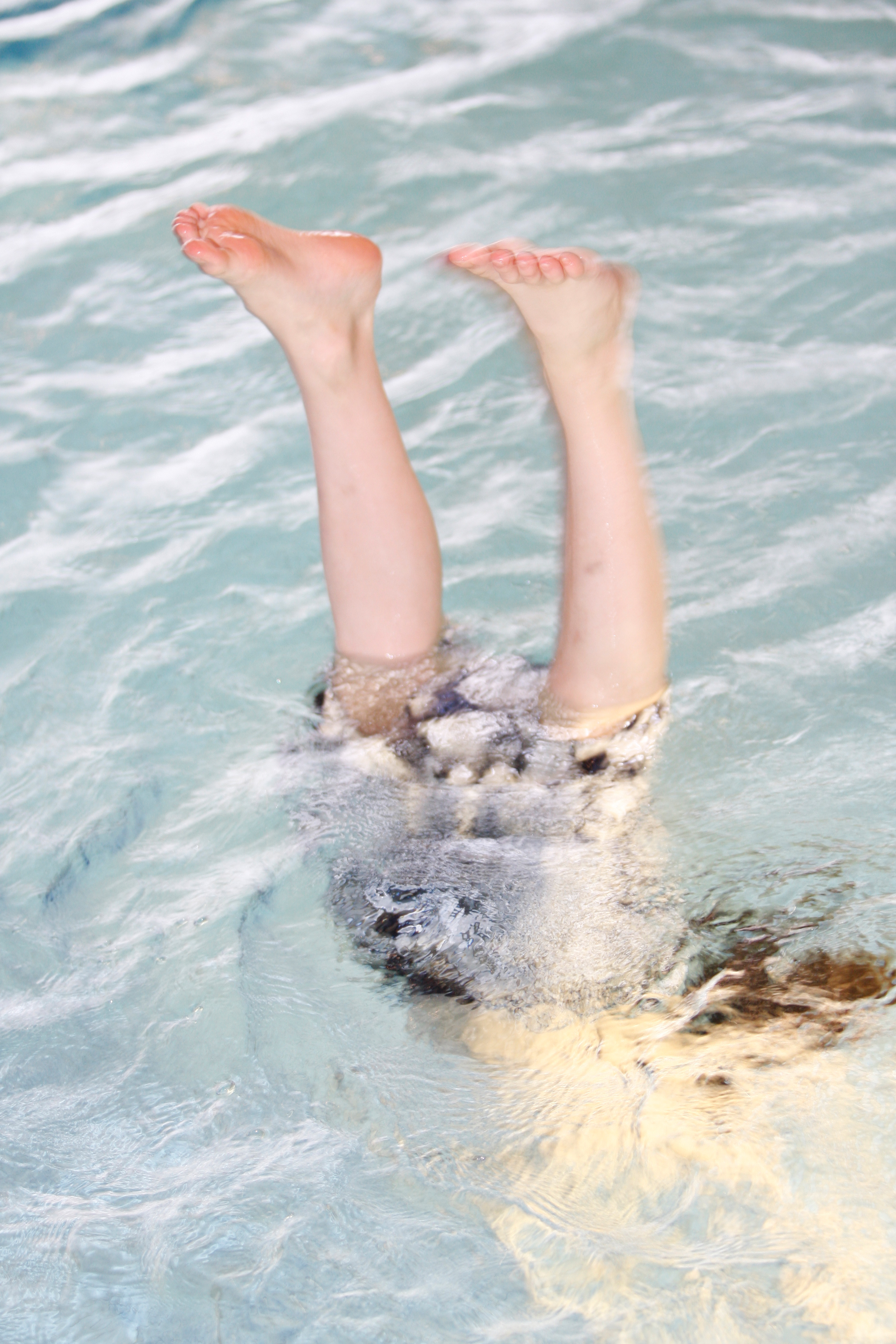 Das Foto zeigt zwei Kinderfüße, die aus dem Wasser schauen. 