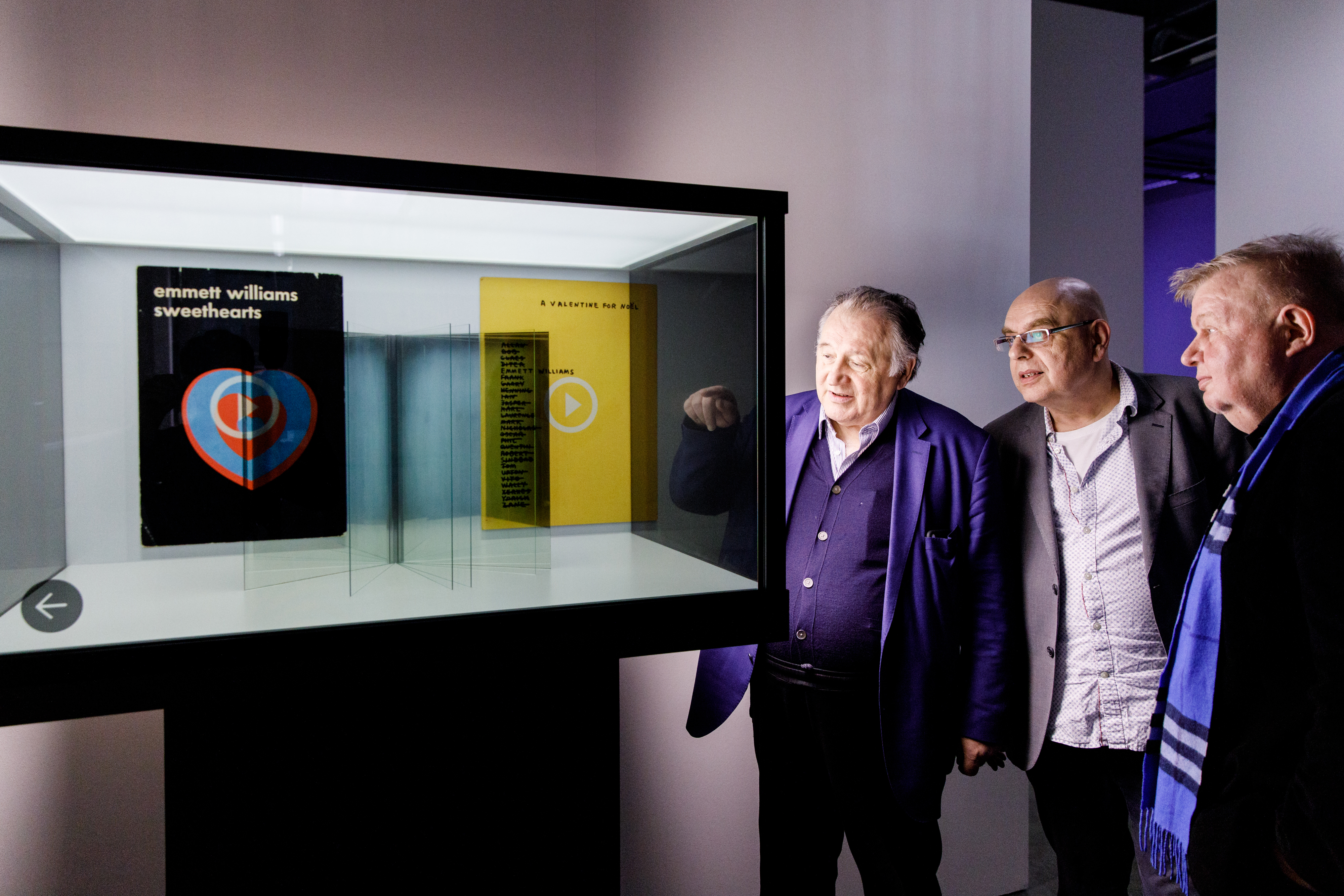 Peter Weibel vor einer Vitrine mit virtuellen Büchern in der Ausstellung »Writing the History of the Future«