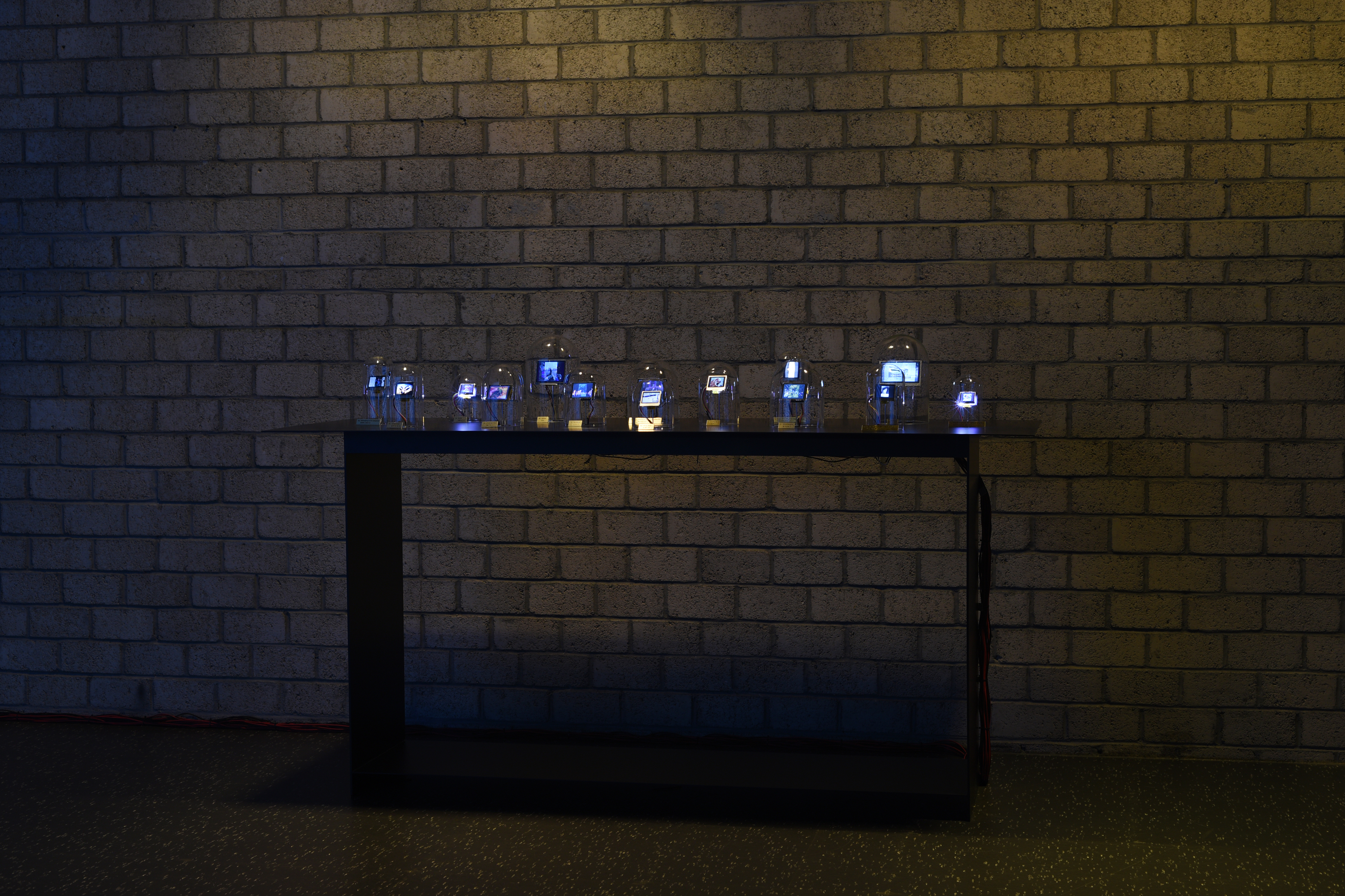 The photo shows a dark table with several glass bells with integrated displays are exposed.