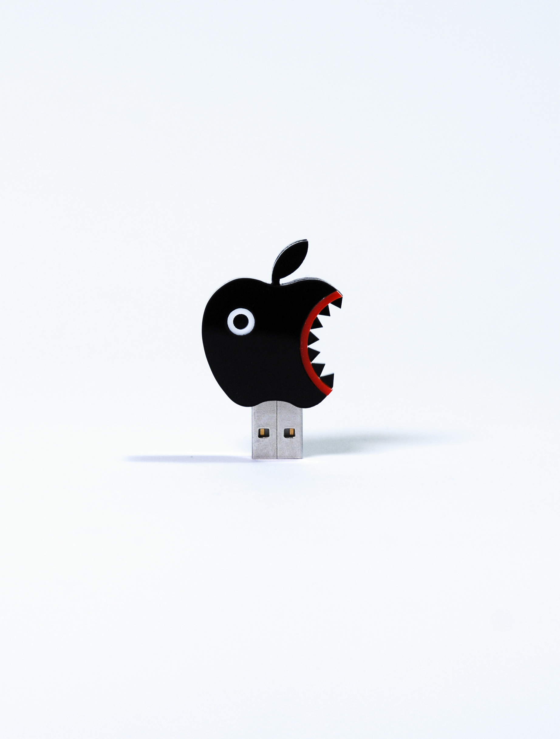 The photo shows a USB stick in the form of a black PacMan-like apple icon.