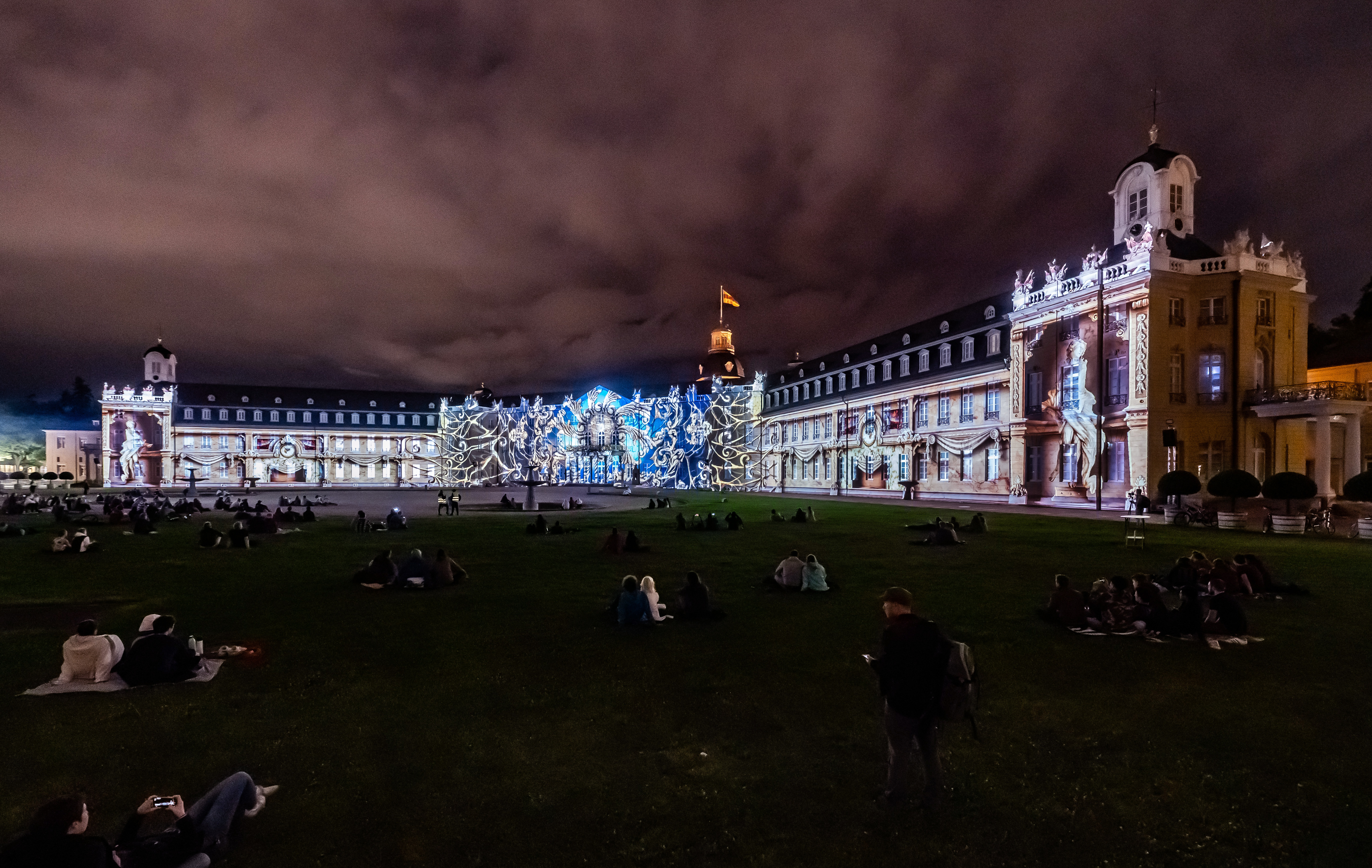 Photo of a colorful projection mapping at night on the baroque Karlsruhe castle.