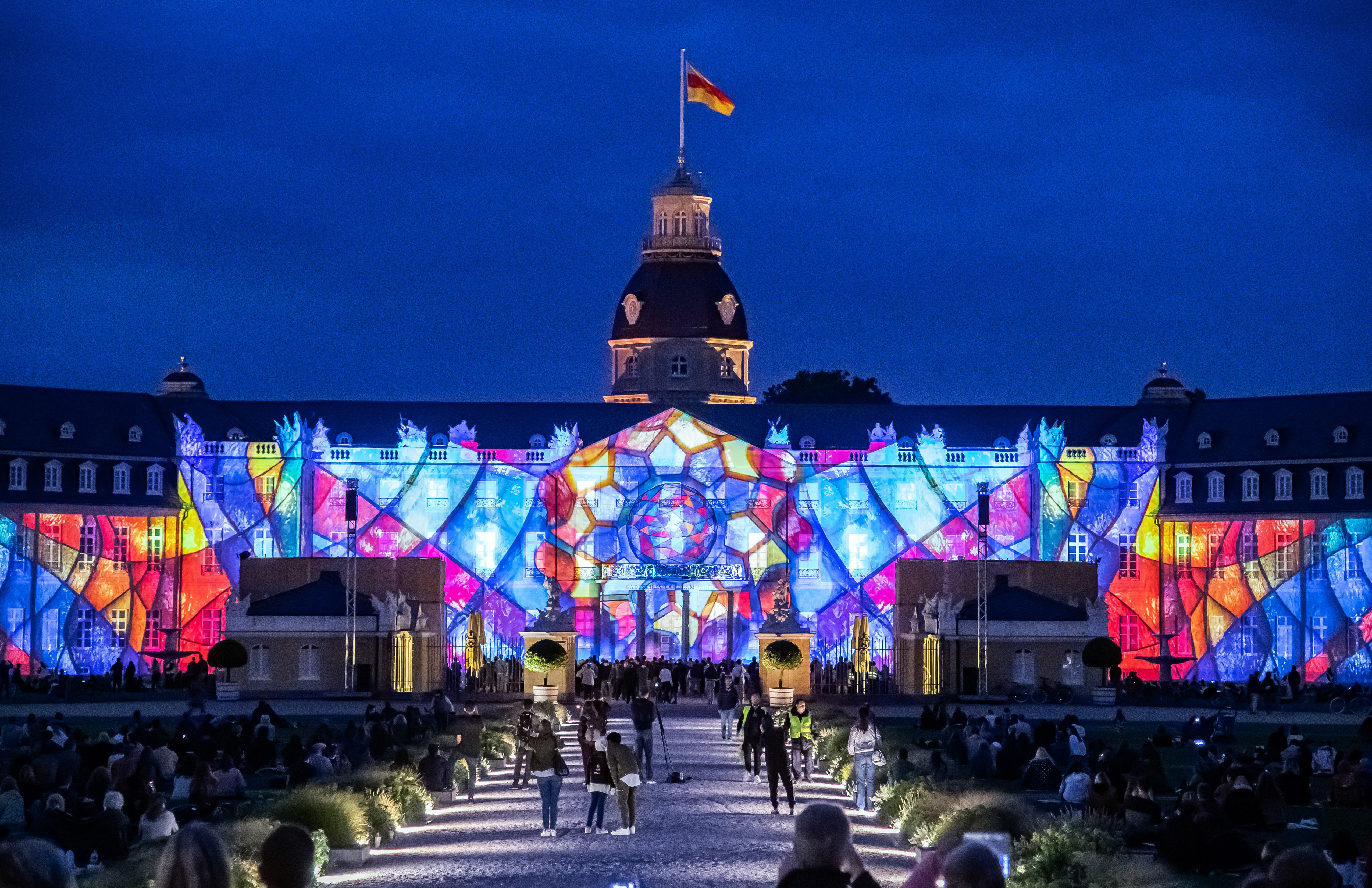 Photo of a colorful projection mapping at night on the baroque Karlsruhe castle.