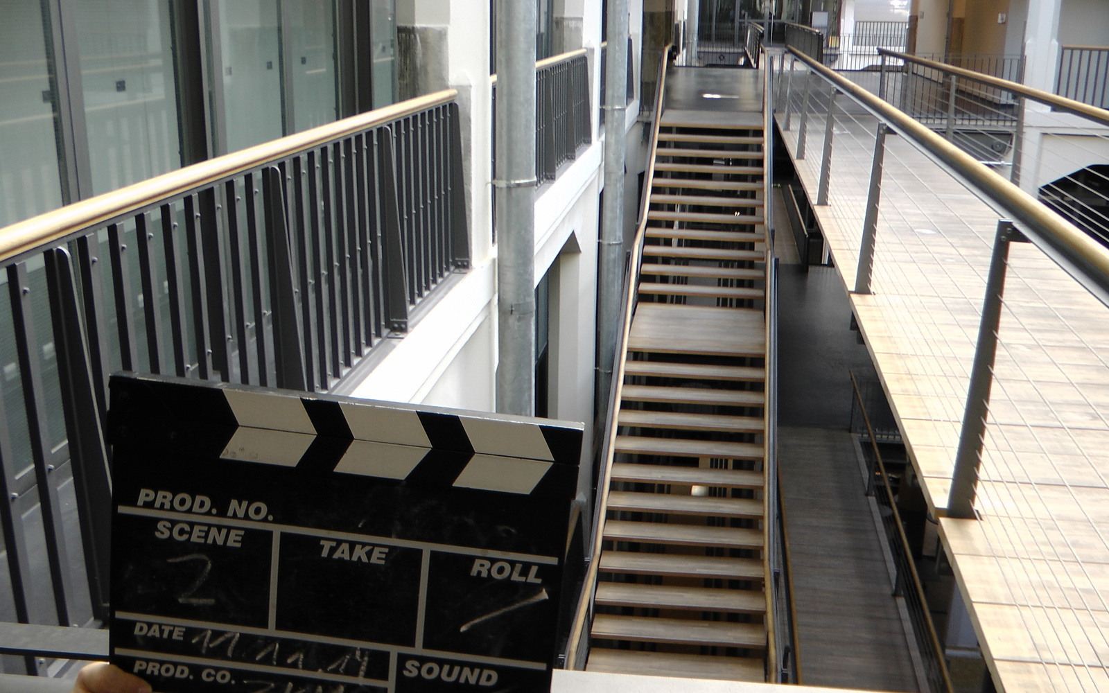 There are little hands of a child visible, they are holding a clapperboard for movies. In the background we can see stairs within the zkm.