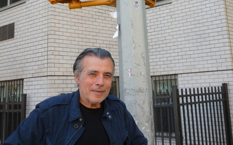 A man standing at an intersection under traffic lights with a red hand on it