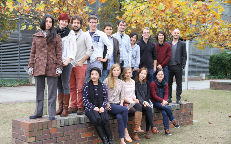 A group of young people sitting and standing on a low brick wall