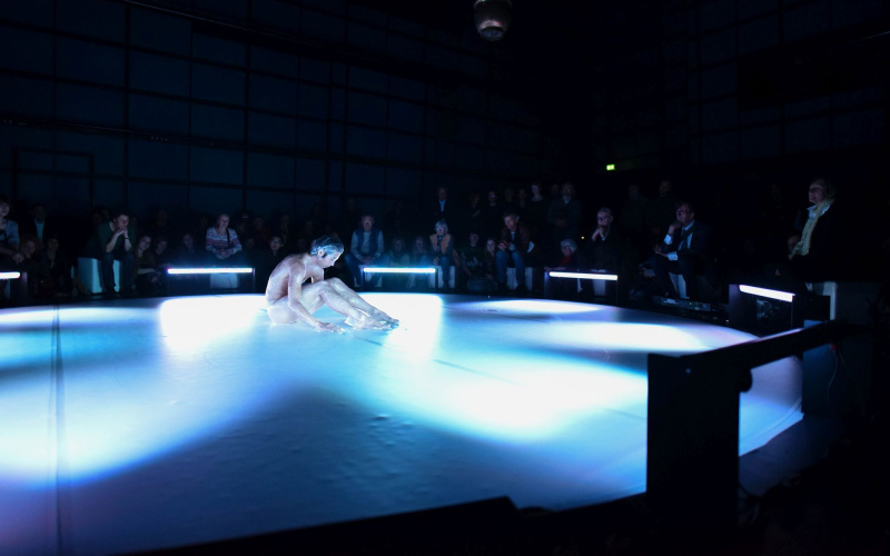 A male person sitting on the floor and is wrapped in a kind of plastic film