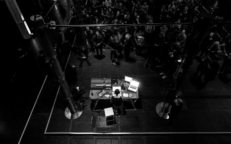 People stand and sit between illuminated speaker towers