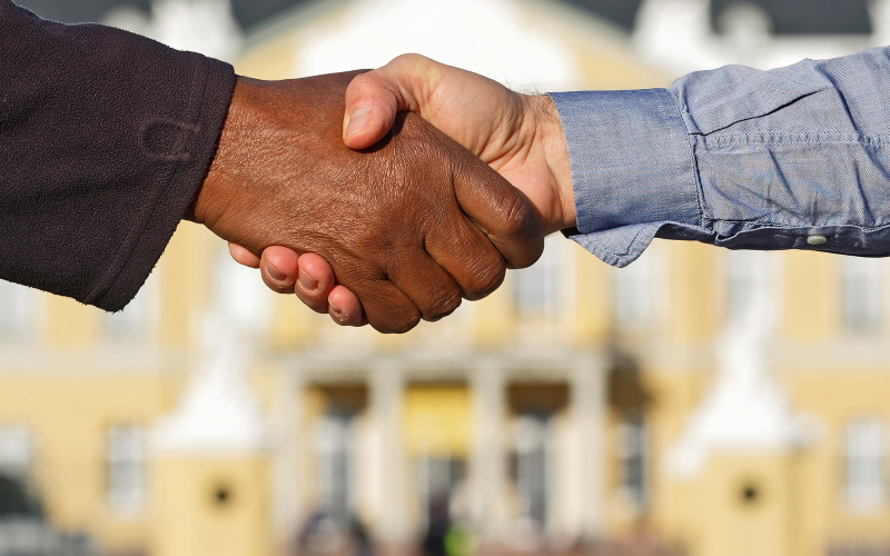 Two people shaking hands, you can see the castle of Karlsruhe in the background.