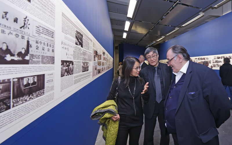 Three people talking in front of some exhibited paintings