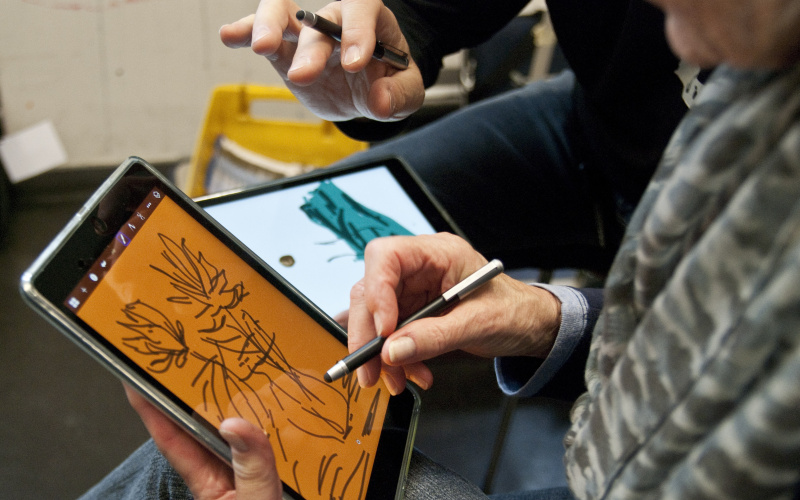 Someone is painting with a stylus, a special pen for displays, on an iPad.