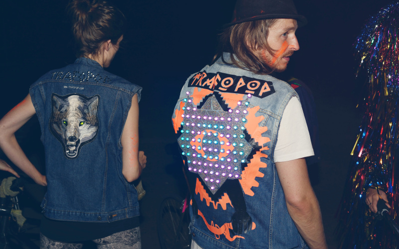 A woman and a man are standing with their backs to the observer - on their jackets there are colourful led's attached