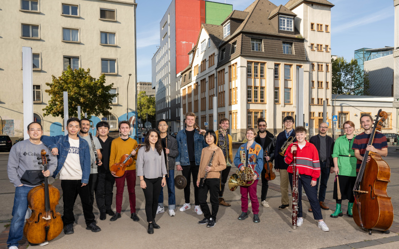 Zu sehen ist eine Gruppe von Personen mit verschiedenen Musikinstrumenten.