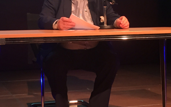 Peter Weibel sitting at a table and reading a text