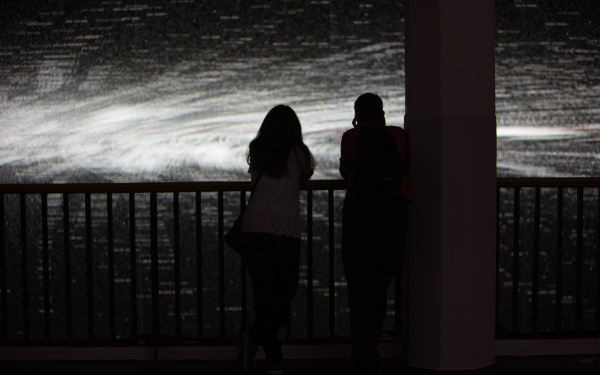 Shadows of two people in front of a black and white projection