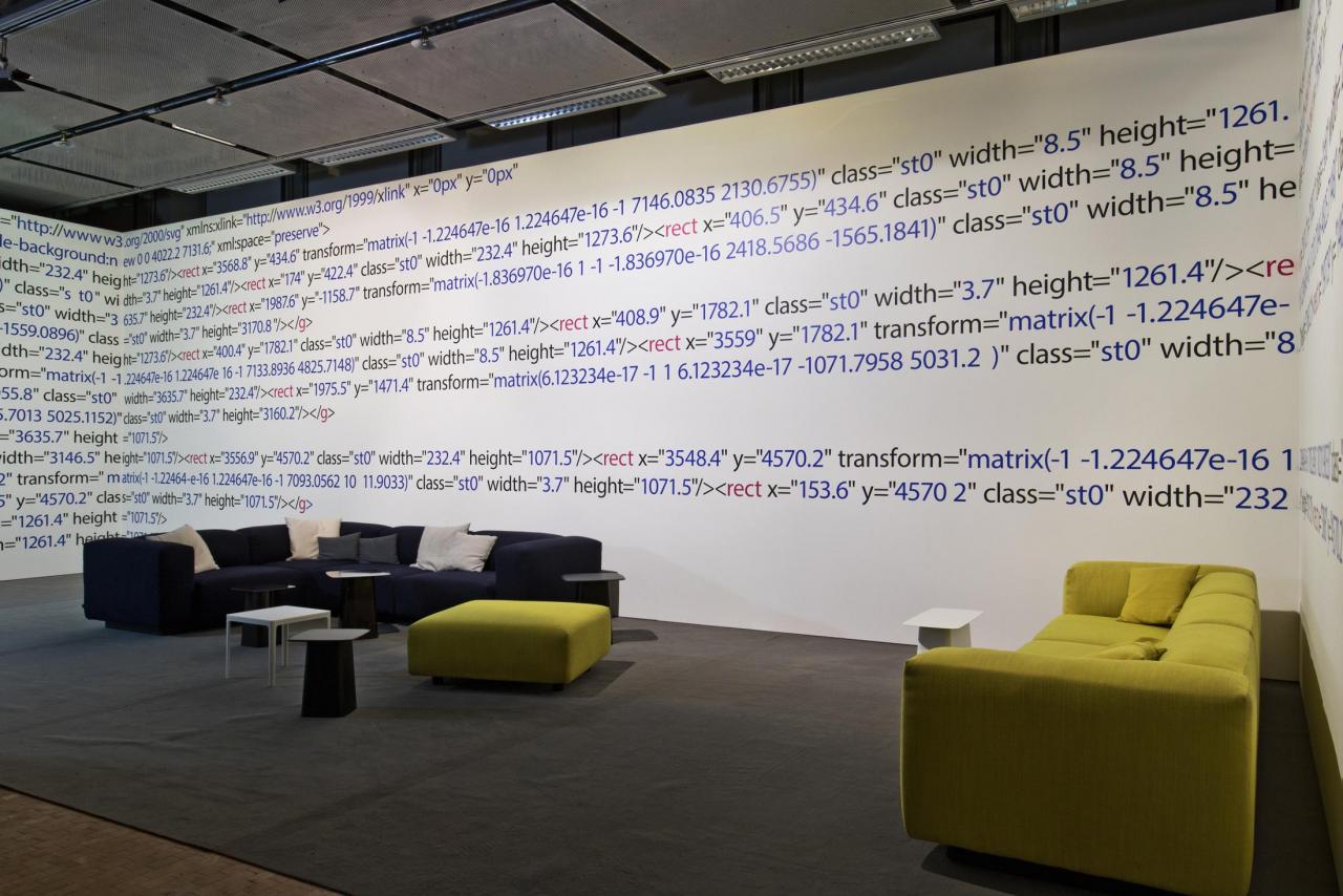 Green and black sofa with seats in front of a wall installation with displayed computer code