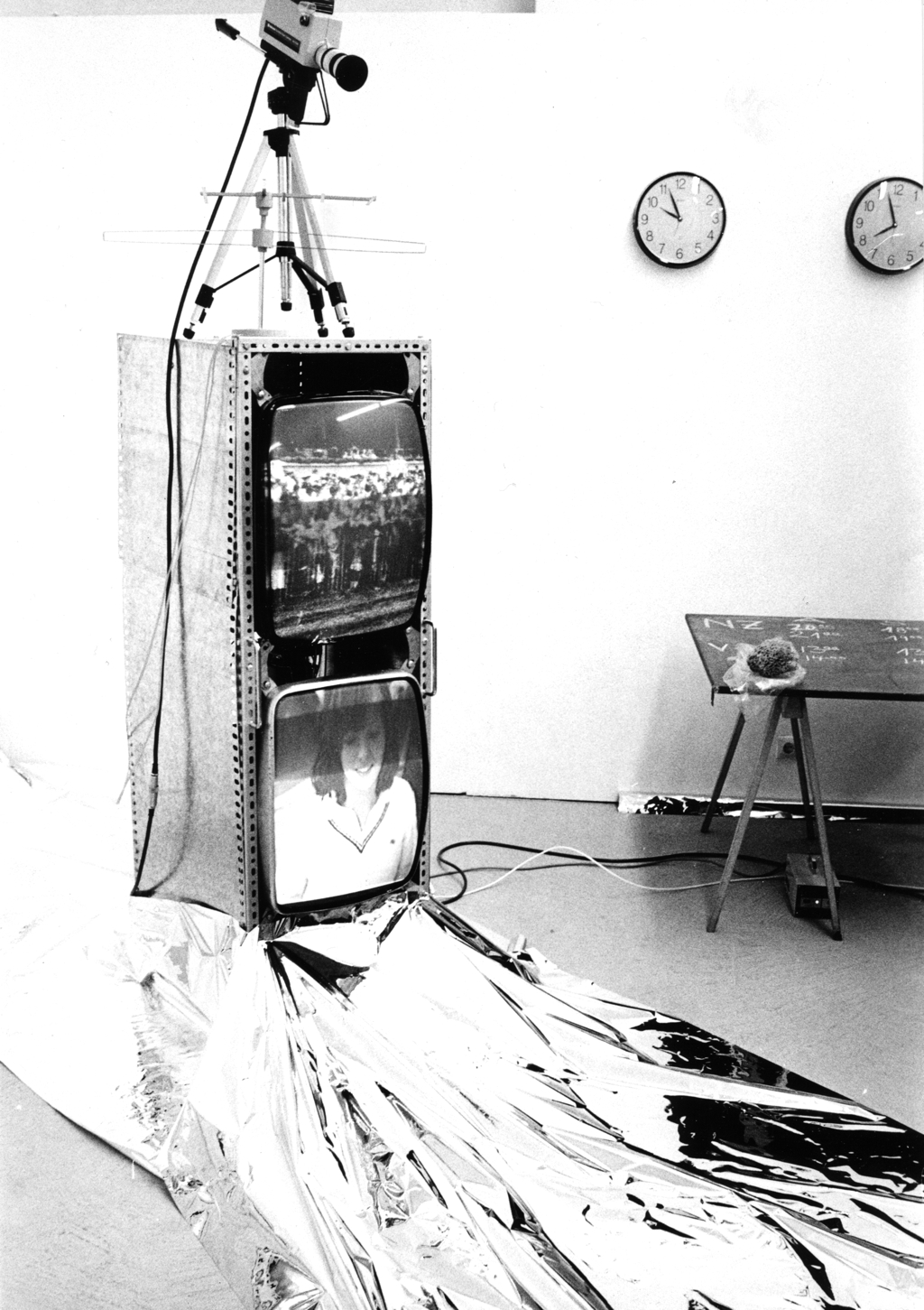 A rack with two screens, a camera on top. On the floor a silver foil.