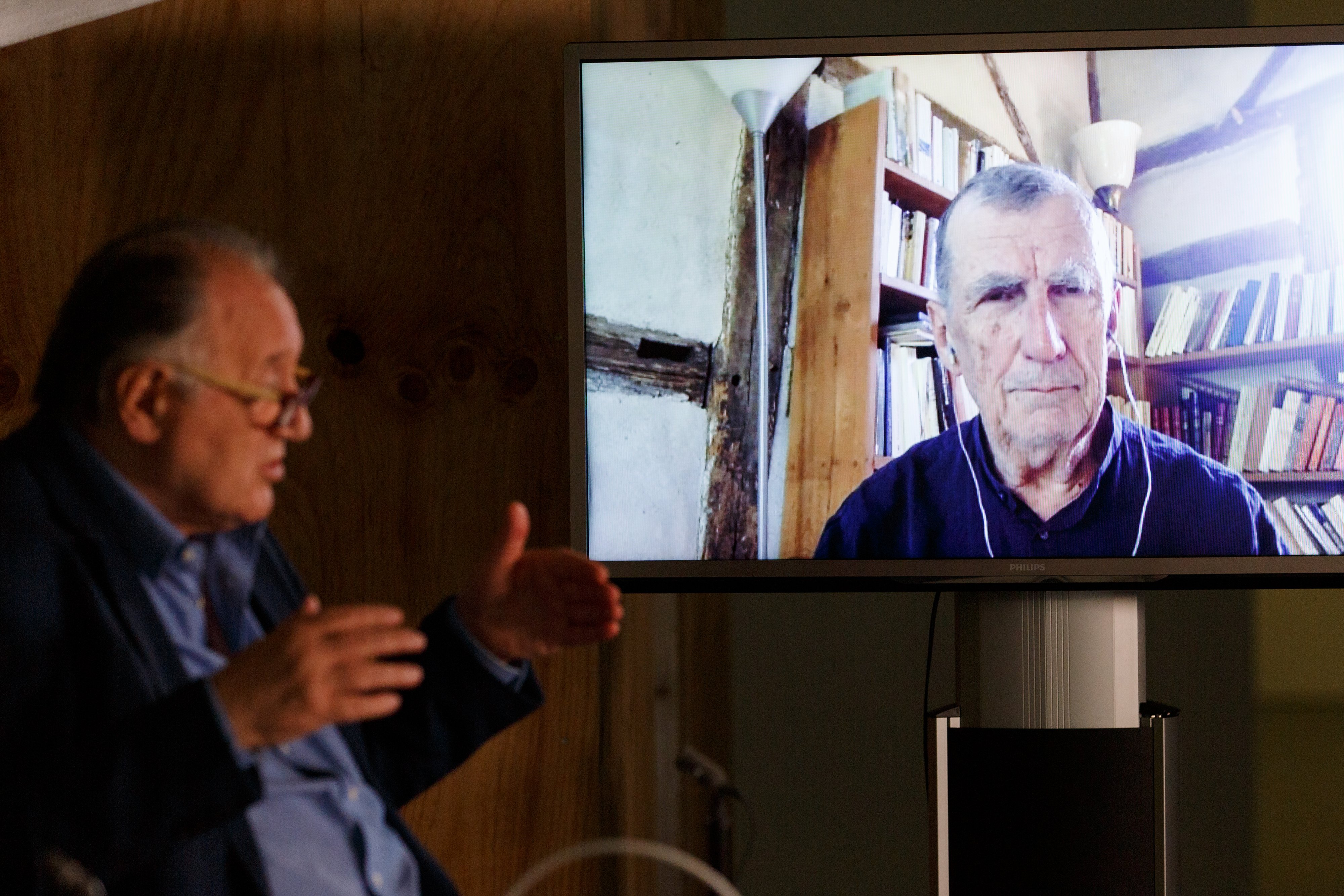 Peter Weibel sits in front of a large screen on which Bruno Latour can be seen.