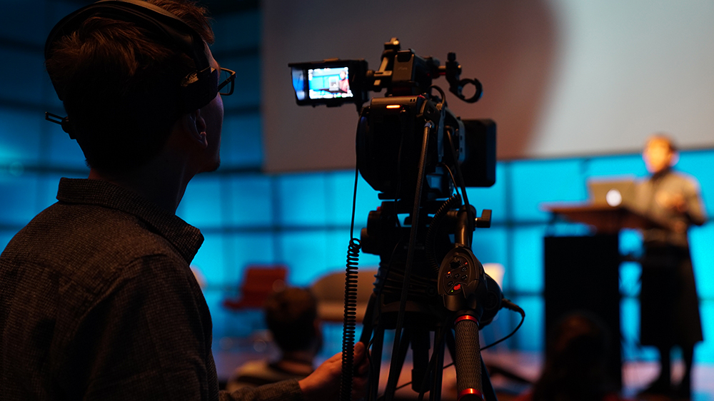 A cameraman looks into the display of a camera. 