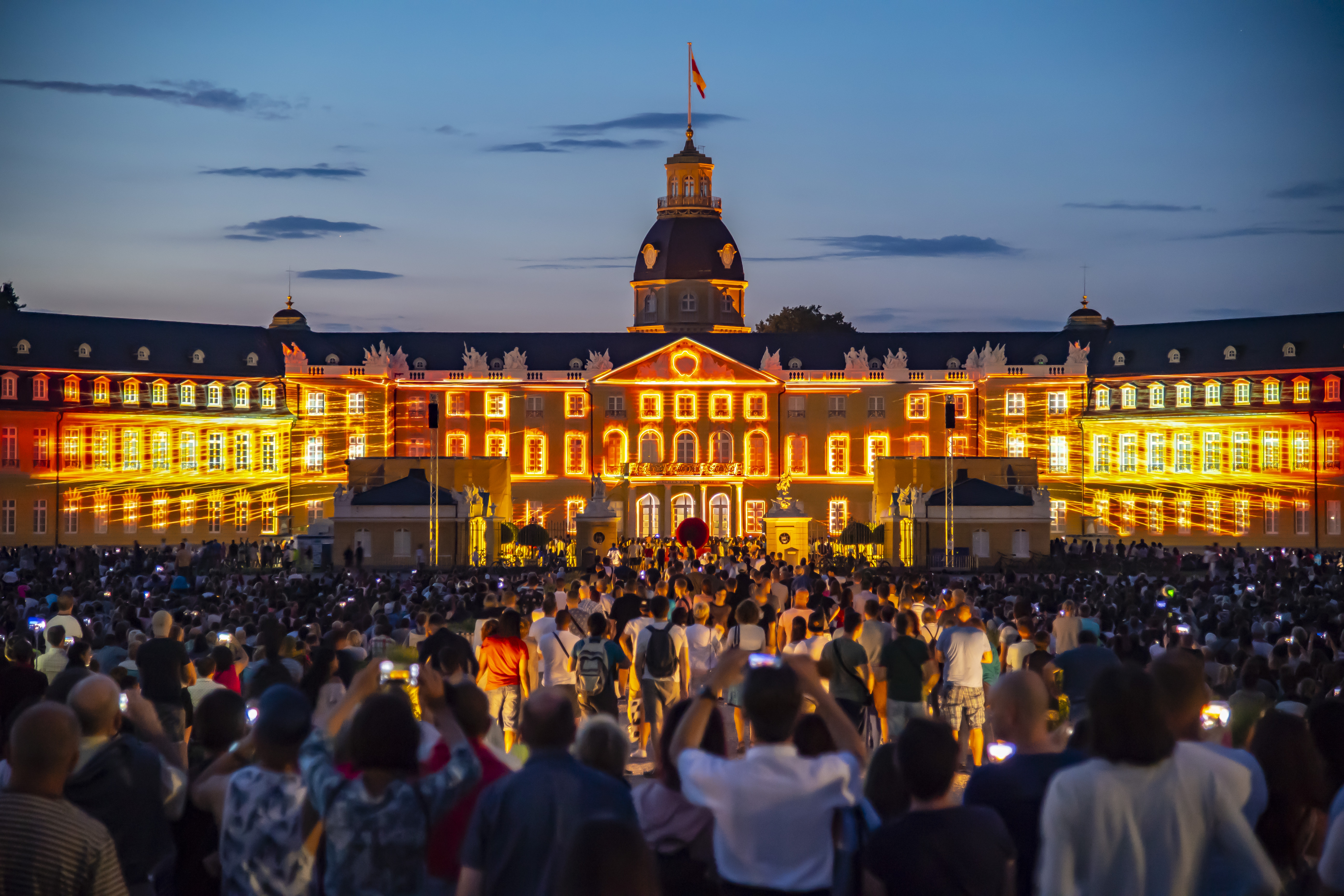 The facade of Karlsruhe Palace is illuminated at night.