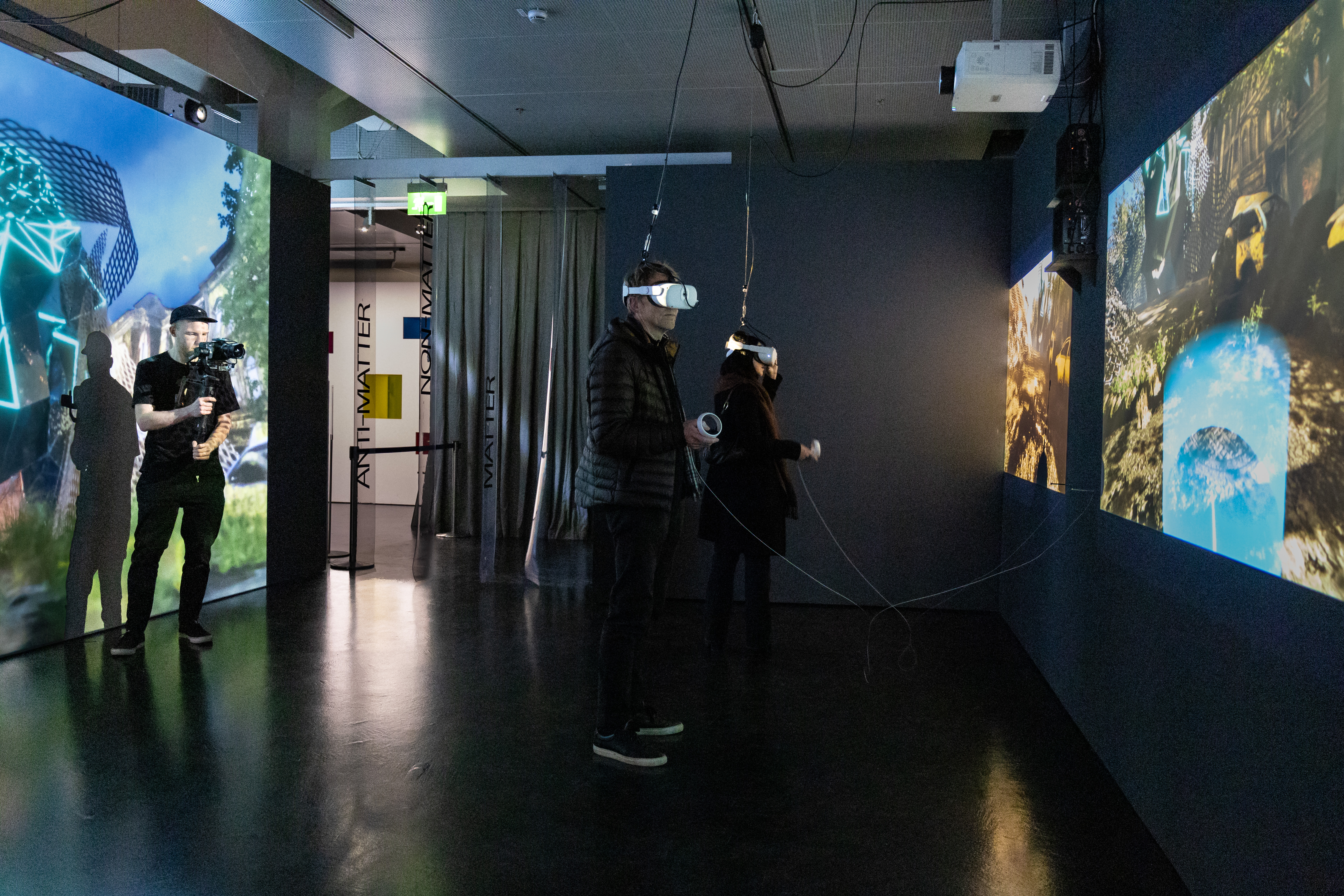 Exhibition view »Matter. Non-Matter. Anti-Matter« at ZKM | Center for Art and Media Karlsruhe, 2022. Two large canvases can be seen on the left and right side. Two people are wearing VR glasses.