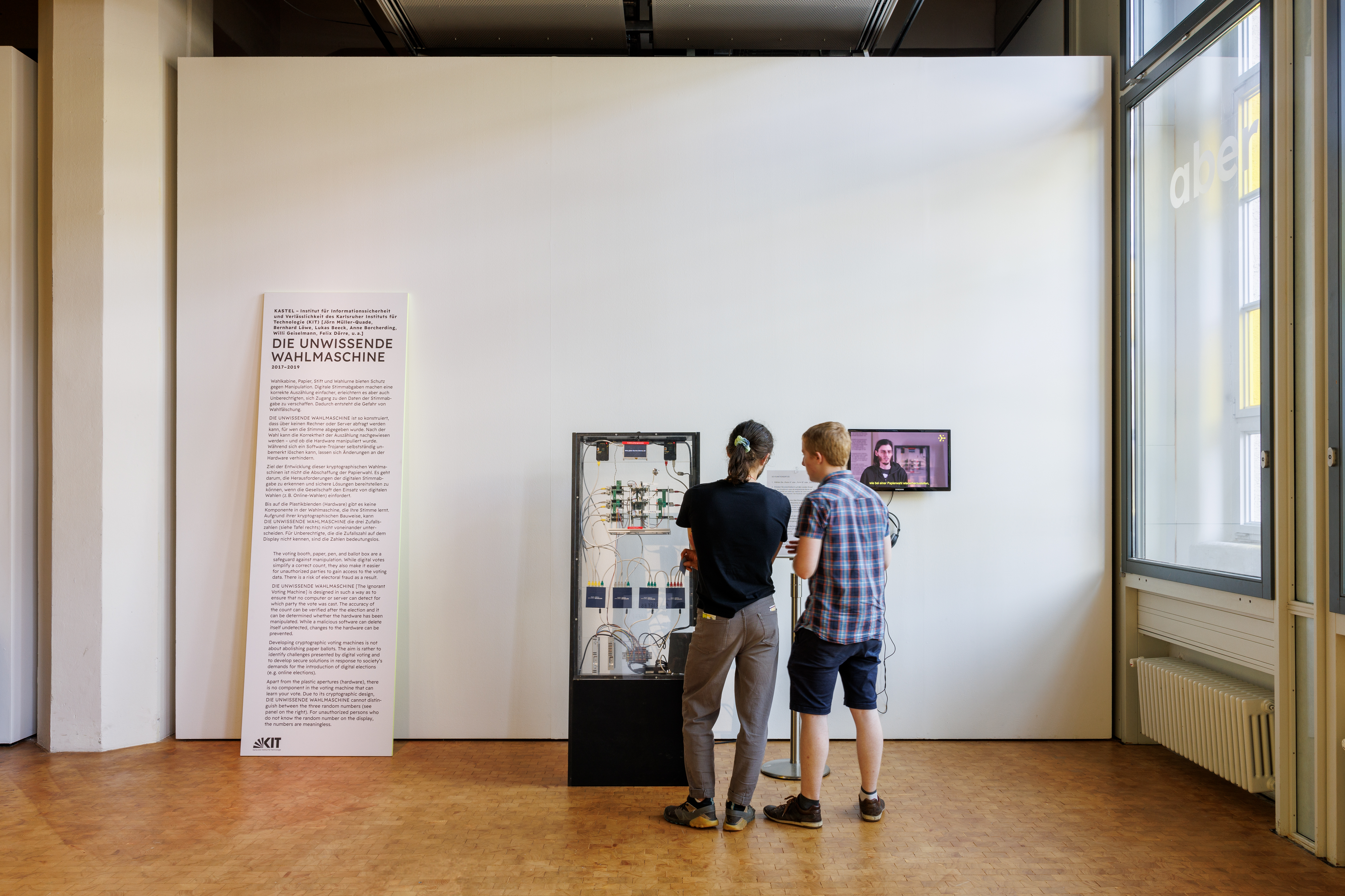 Zwei Personen stehen vor der "Unwissenden Wahlmaschine", eine interaktive Installation