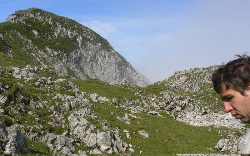 Im Hintergrund Berge, im rechten Bildrand ein Gesicht eines jungen Mannes