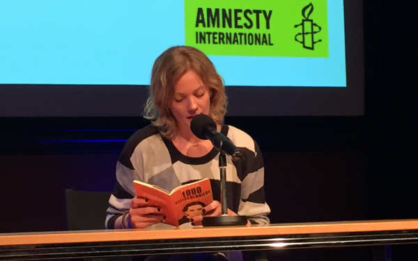 A woman sitting at a table and reading from a book