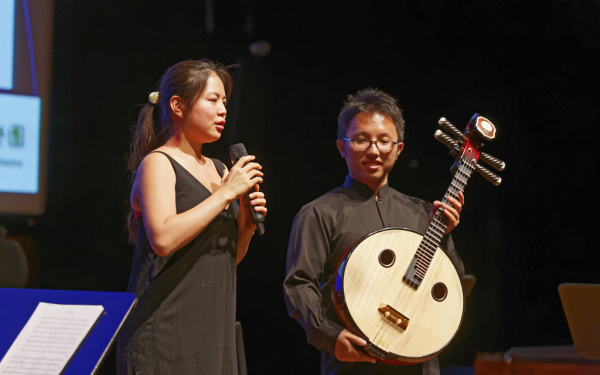 Eine Frau mit Mikrofon und ein Mann mit einer Art Gitarre